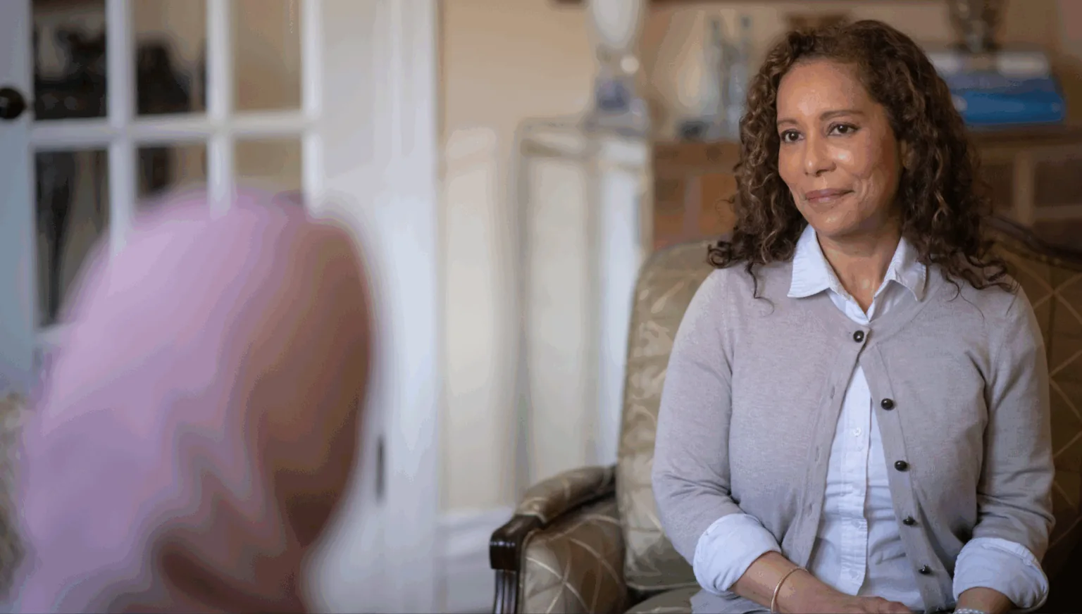 Woman sitting in an armchair, listening attentively during a conversation