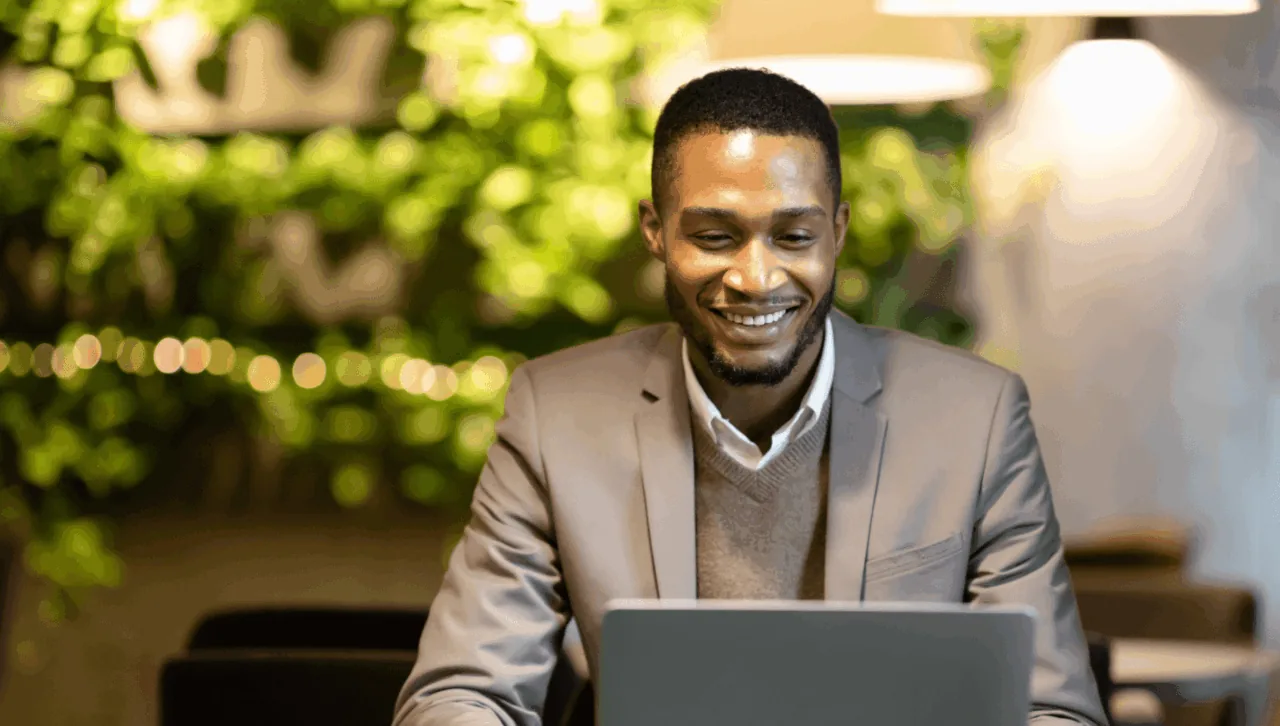 Smiling man in a blazer working at a laptop